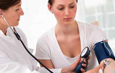 Ärztin misst den Blutdruck und Puls bei Patientin